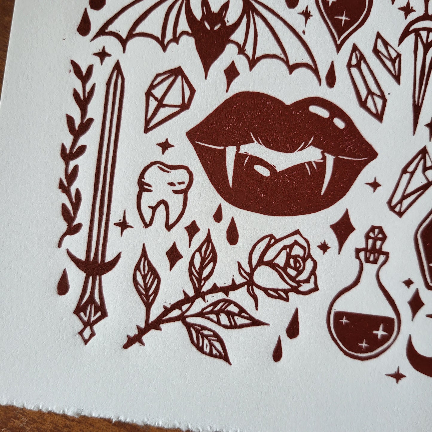 Linocut print of a vampire witch featuring lips, rose, sword, and other elements on a white background
