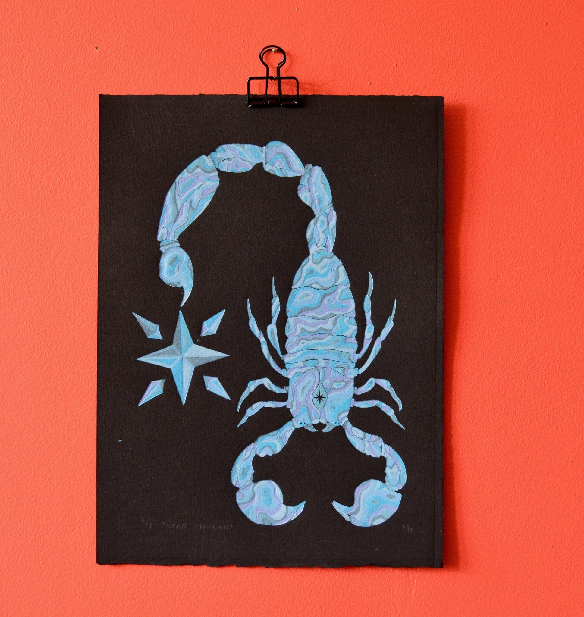 Blue scorpion original art print on a black background with a star, pinned to an orange wall.