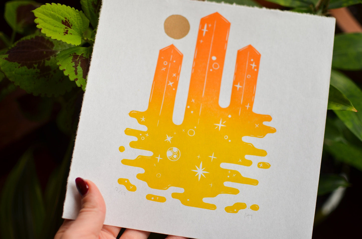 Handmade paper with a colorful space themed tower design held by a person against a natural background.