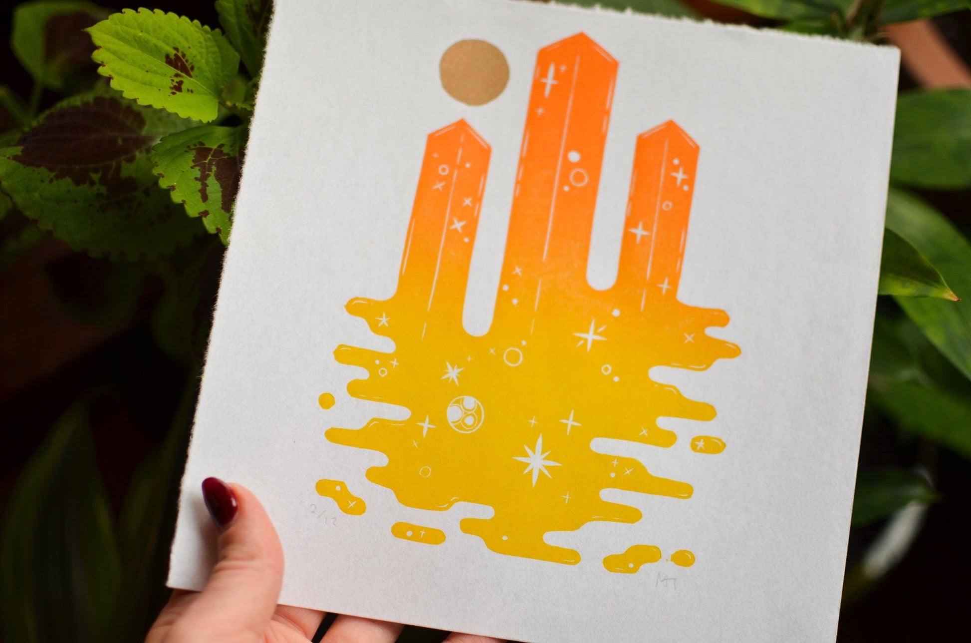 Handmade paper with a colorful space themed tower design held by a person against a natural background.