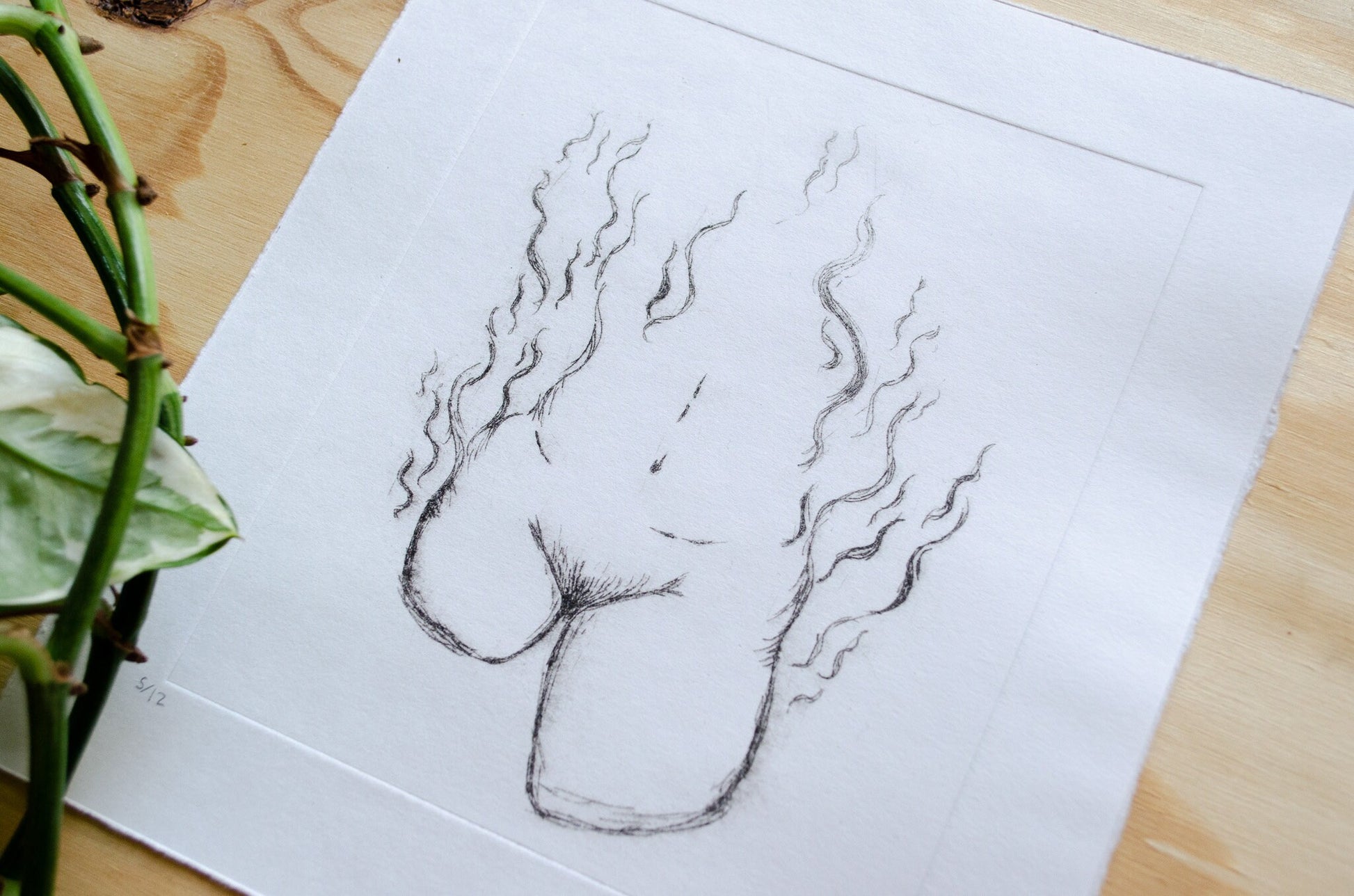 A dry point etching of an abstract female form on a wooden table