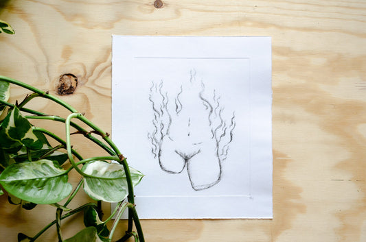 A dry point etching of an abstract female form sits on a wooden table