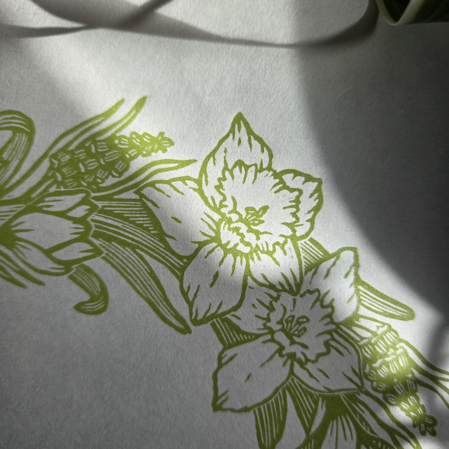 Close up of a linocut print of a light green Spring Floral Wreath, showing two daffodil flowers