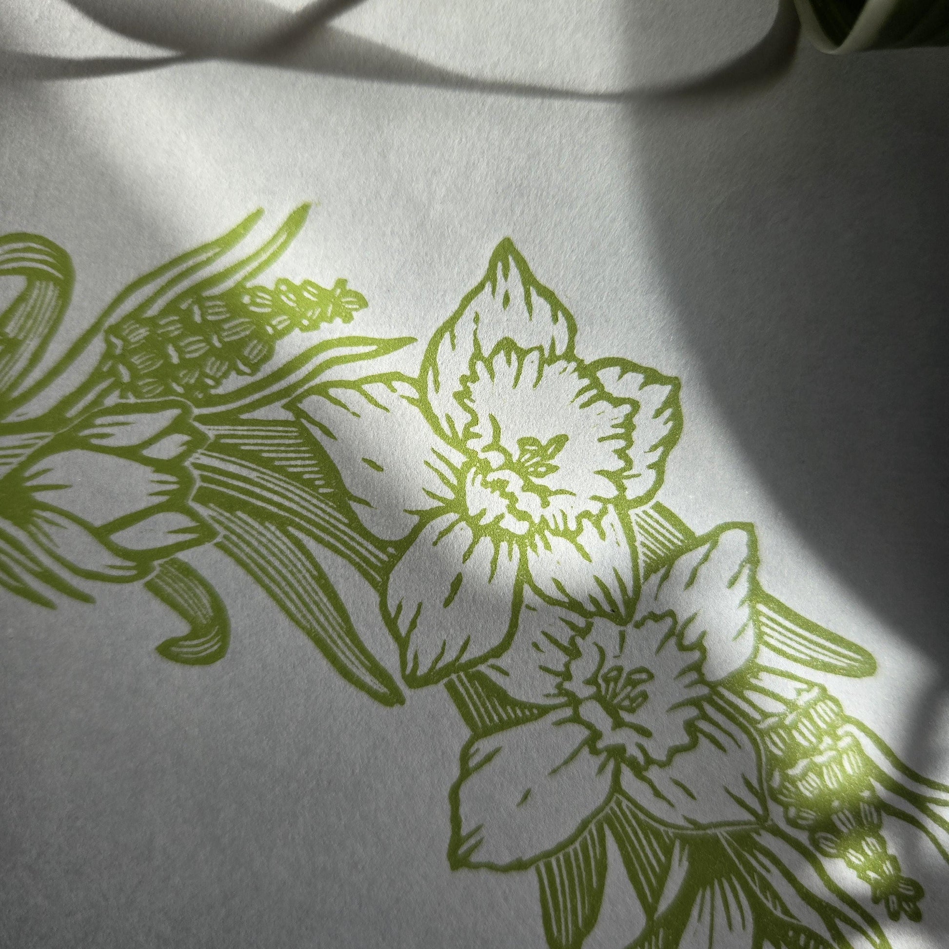 Close up of a linocut print of a light green Spring Floral Wreath, showing two daffodil flowers