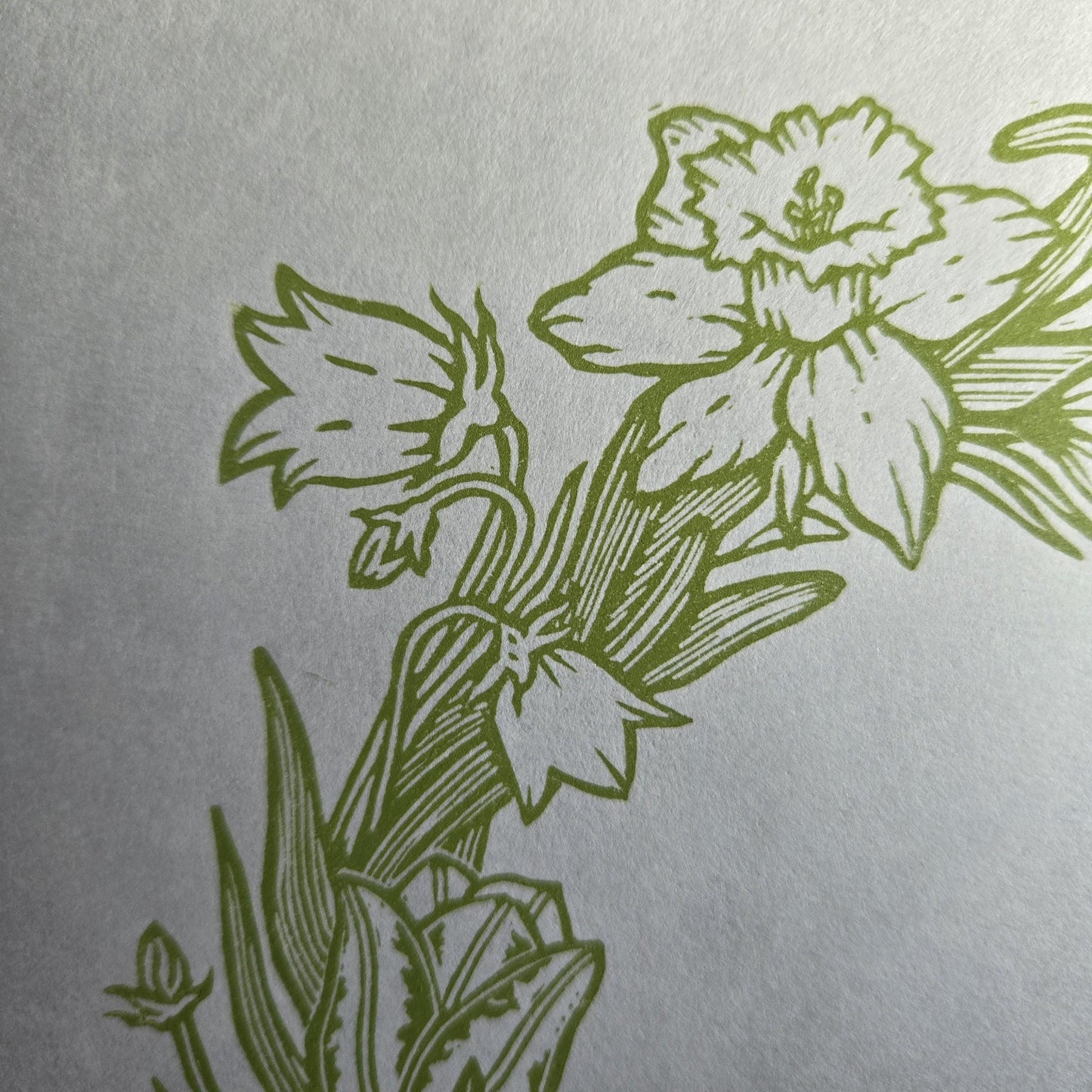 Close up of a linocut print of a spring wreath showing a daffodil and harebell