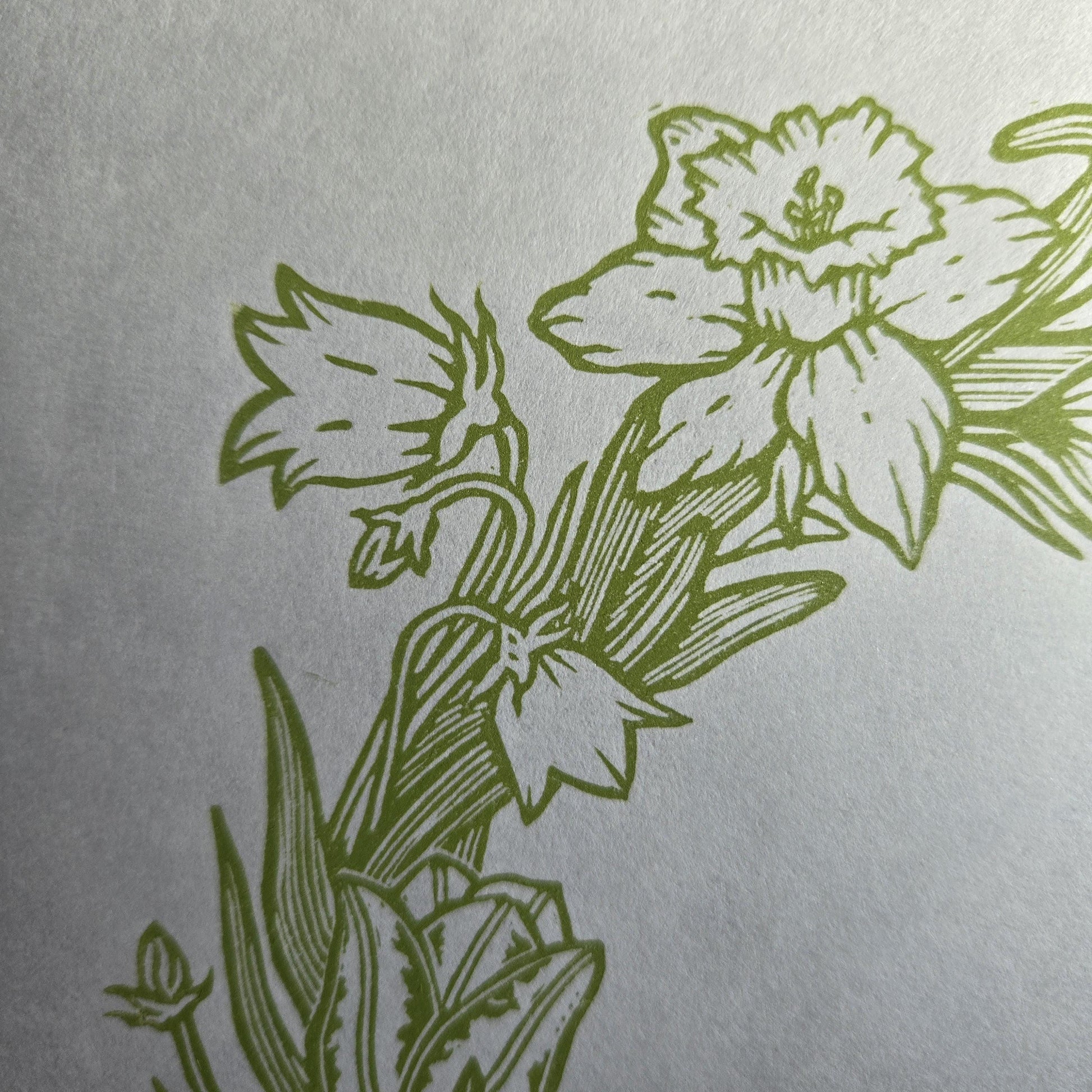 Close up of a linocut print of a spring wreath showing a daffodil and harebell